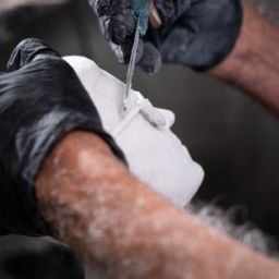 Hand detailing a custom white bonded marble portrait bust at Statues.com to achieve museum-quality realism and fine artistic detail.