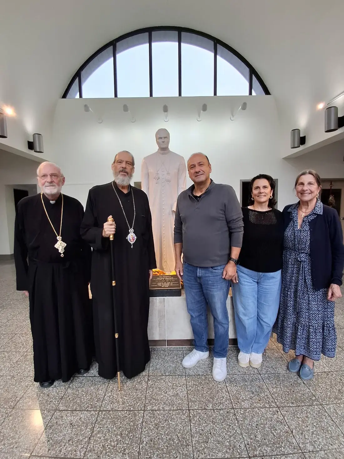 Vasilios and Victoria Karpos with an Orthodox clergyman beside the Metropolitan Orestes Chornock statue
